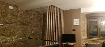 a room with a stone wall and a television at La Casita de Sofía in Monforte de Lemos