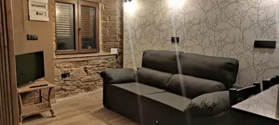 a living room with a leather couch and a television at La Casita de Sofía in Monforte de Lemos
