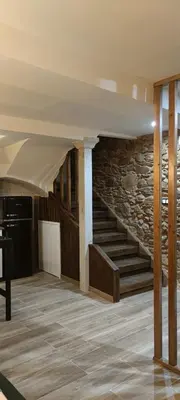 a living room with a stone wall and stairs at La Casita de Sofía in Monforte de Lemos
