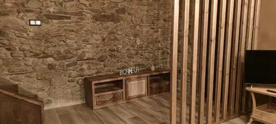 a living room with a stone wall and a television at La Casita de Sofía in Monforte de Lemos
