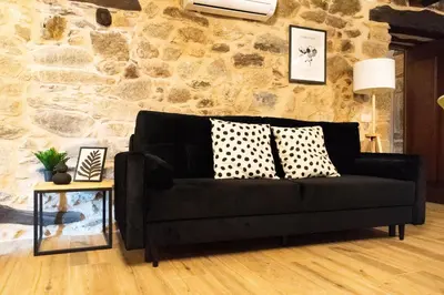 a black couch in a living room with a stone wall at Ecolagar O Barqueiro in Pantón