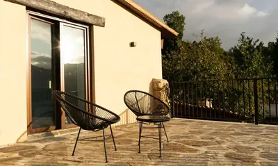two chairs sitting on a patio near a building at Ecolagar O Barqueiro in Pantón