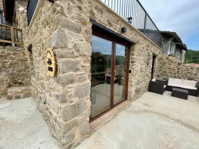 a stone building with a large glass window at Ecolagar O Barqueiro in Pantón