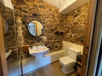a stone bathroom with a sink and a mirror at Ecolagar O Barqueiro in Pantón