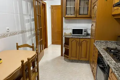 a kitchen with wooden cabinets and a table and a microwave at Oktheway Calvo Sotelo in Sarria