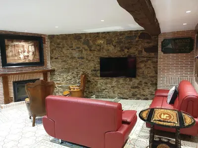 a living room with red leather furniture and a stone wall at Casa Honorio in Santa Marina del Sil