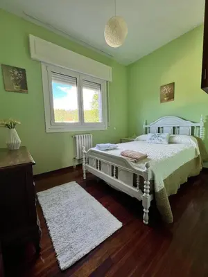 a bedroom with a white bed in a green room at Casa Lola in Teo