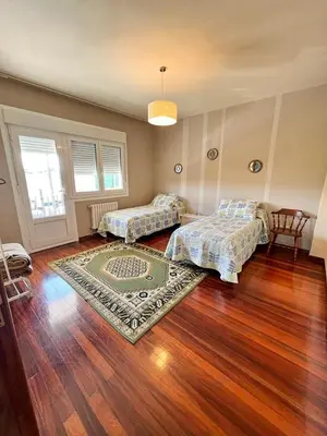 a bedroom with two beds and a rug on a wooden floor at Casa Lola in Teo