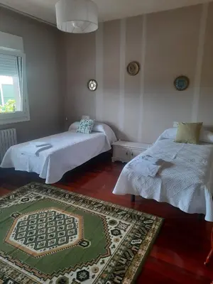 a bedroom with two beds and a rug on the floor at Casa Lola in Teo