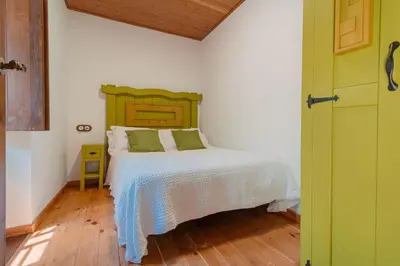 a bedroom with a white bed with a green headboard at Casa Escondida Aveiga in Chantada