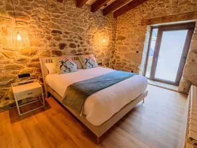 a bedroom with a bed in a stone wall at Casa Escondida Aveiga in Chantada
