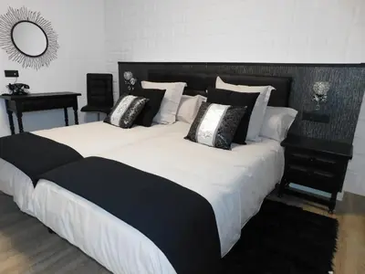 a large bed with black and white pillows on it at HOTEL TERRA GALEGA MEIGA in Monforte de Lemos