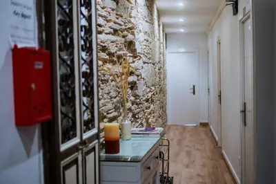 a hallway with a stone wall and a table with a candle at Hostal Santa Cruz in Santiago de Compostela