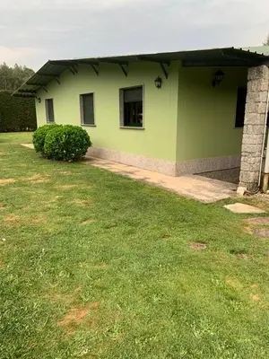 a green building with a grass yard in front of it at Villa Bimba, alojamiento con piscina y barbacoa in Caldas de Reis
