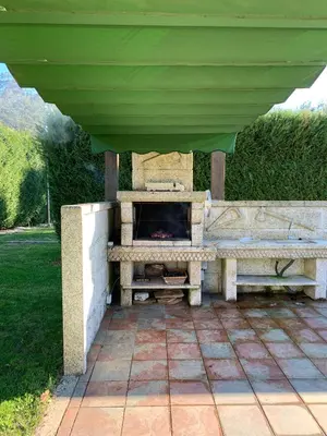 a stone fireplace under awning on a patio at Villa Bimba, alojamiento con piscina y barbacoa in Caldas de Reis