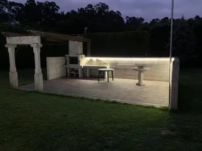 a backyard with a bench and a table at night at Villa Bimba, alojamiento con piscina y barbacoa in Caldas de Reis