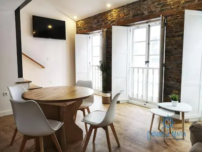 a dining room with a wooden table and chairs at Cabanela Maitia Apto Telmo Duplex in Ribadeo