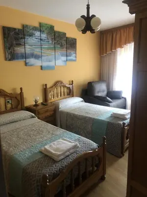 a bedroom with two beds and a chair and a couch at Habitaciones A Casa de Pepe in Tríacastela