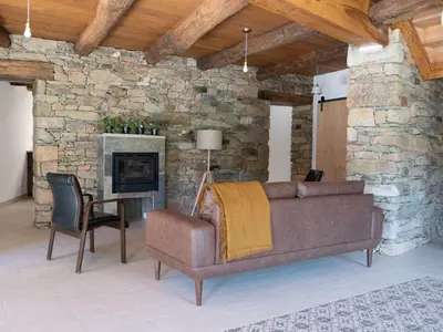 a living room with a couch and a stone wall at CASA TERRA ALMA in Laza