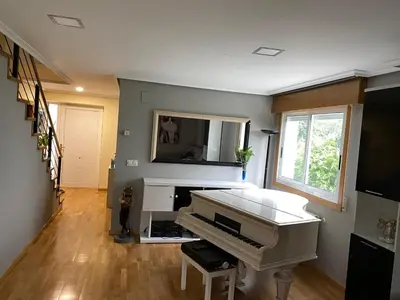 a living room with a white piano and a television at CHALET A SOLO 5 MIN DE OURENSE CIUDAD con jardín y barbacoa in Ourense