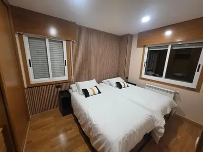 a bedroom with two beds and two windows at CHALET A SOLO 5 MIN DE OURENSE CIUDAD con jardín y barbacoa in Ourense