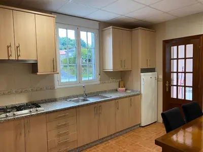 a kitchen with wooden cabinets and a white refrigerator at Fonte do Torno in A Coruña