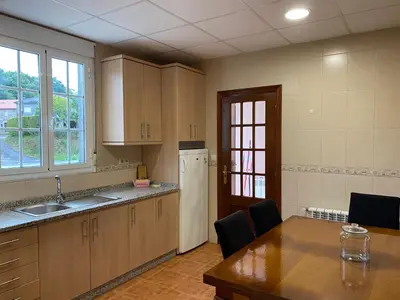 an empty kitchen with a table and a refrigerator at Fonte do Torno in A Coruña