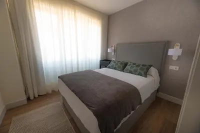 a bedroom with a large bed and a window at LA CASITA DE FINA in Caldas de Reis