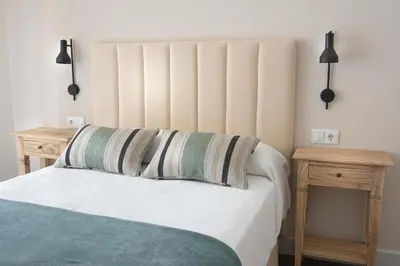 a bedroom with a bed with two nightstands and two tables at LA CASITA DE FINA in Caldas de Reis