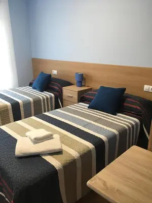two beds in a hotel room with towels on them at Pensión Santirso in Palas de Rei