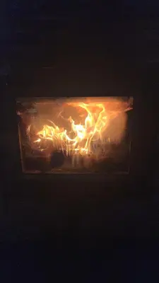 a fireplace with fire in it at night at CASAPUEBLO Arzúa in Campo