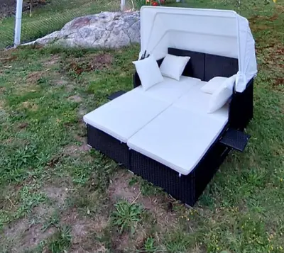 a white bed with pillows on the grass at O Cobo Vacacional in Padrón
