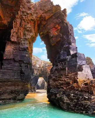 an arch in a rock formation in the water at O Xuncal in Barreiros