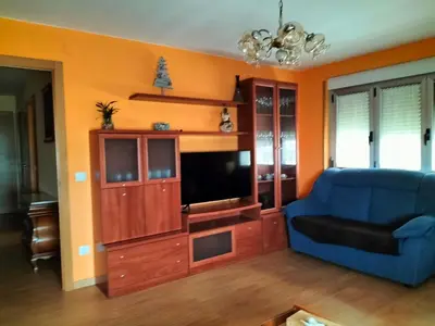 a living room with a blue couch and a television at FOZ PLAYA RAPADOIRA in Foz