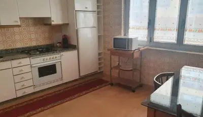 a kitchen with a refrigerator and a table with a microwave at FOZ PLAYA RAPADOIRA in Foz