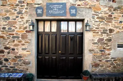 a black door in a stone building with a sign on it at Casa do Hiebra Alojamiento Rural Ribeira Sacra in Castroncelos