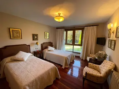 a bedroom with two beds and a chair and a window at Casa rural en entorno privilegiado in Valongo