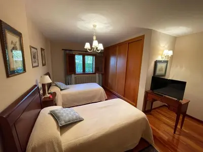 a bedroom with two beds and a flat screen tv at Casa rural en entorno privilegiado in Valongo