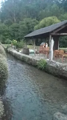 a river with a gazebo and a table and chairs at A Casa das Augas in Mondoñedo