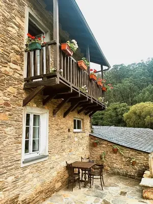 a patio with a table and a balcony on a building at A Casa das Augas in Mondoñedo