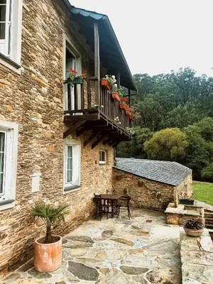 a stone building with a table and a balcony at A Casa das Augas in Mondoñedo