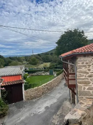 a house with a stone wall next to a road at Casa Anduriña in Ourense