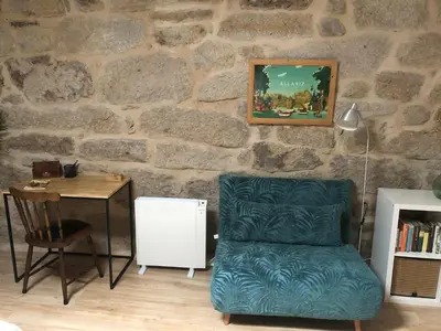 a living room with a chair and a table and a stone wall at Casa Anduriña in Ourense