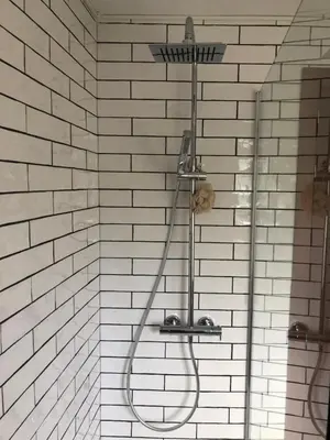 a shower in a bathroom with a white brick wall at Casa Anduriña in Ourense