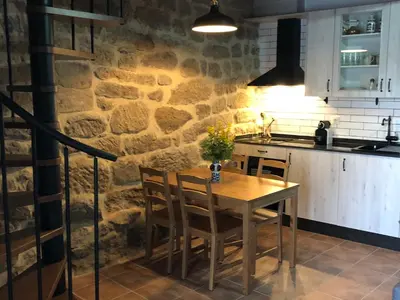 a kitchen with a wooden table and a stone wall at Casa Anduriña in Ourense