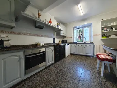 a large kitchen with white cabinets and black appliances at Casa Arquella in Cartavio