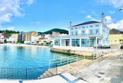 a large white building next to a body of water at The Cliffs - Sunset Village Beach 3E in Viveiro