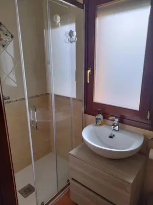 a bathroom with a glass shower and a sink at O Pedregal in Burela de Cabo