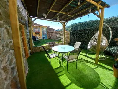 a patio with a table and chairs on the grass at Rincón del Viso in Ourense