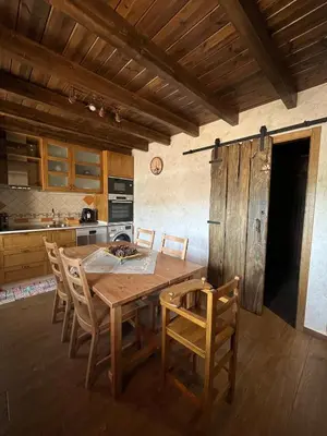 a kitchen with a wooden table and chairs at La CasuKa VUT Fabero in Fabero